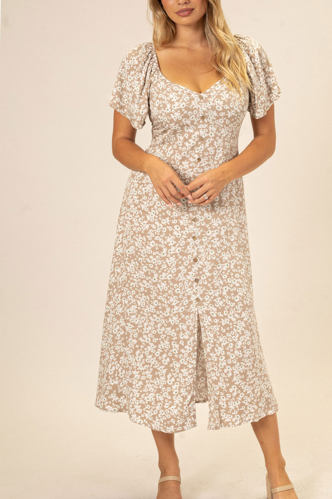 A beige and white floral printed midi dress with a fitted bodice, puff sleeves, and buttons down the front.