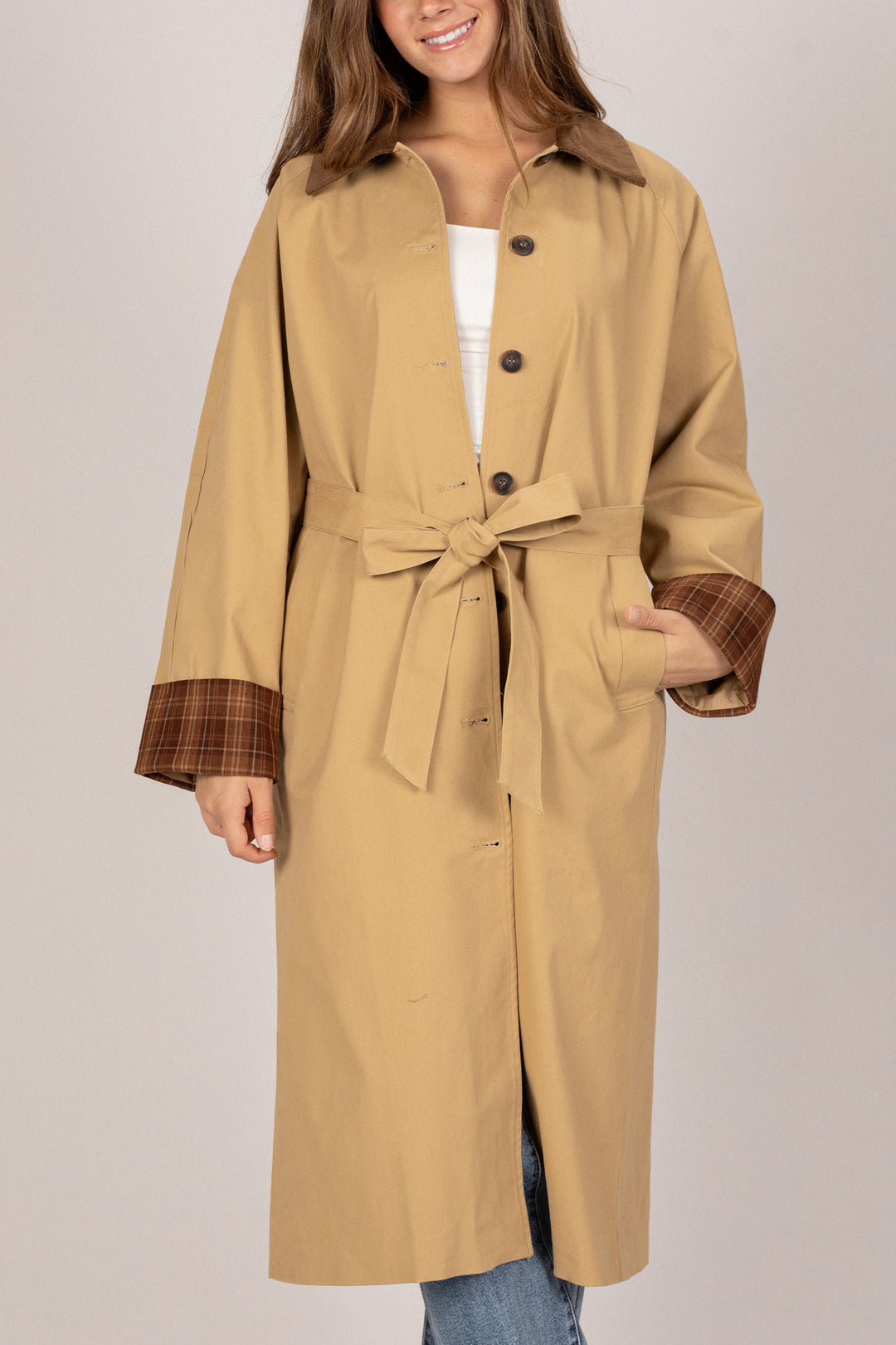 A tan, belted coat with a corduroy collar and plaid-lined cuffs, showcasing a versatile and stylish outerwear piece.