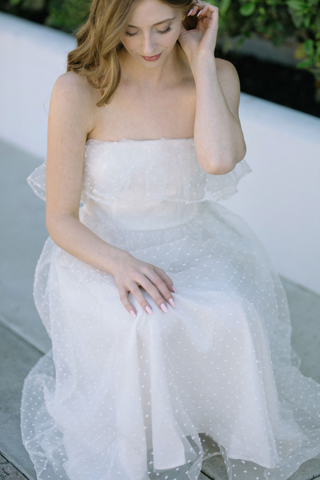 A strapless white tulle midi dress with a ruffled bodice, featuring delicate polka dot embellishments and a flowing skirt.