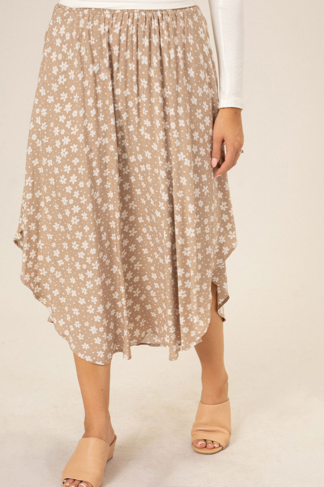 A mid-length, floral print skirt with a rounded hem in a beige and white color scheme, featuring an elastic waistband.