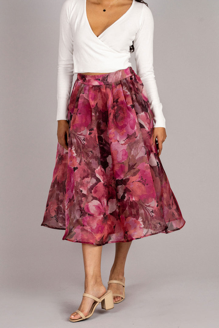A floral midi skirt with a vibrant pink, orange, and purple floral pattern, featuring a high-waisted A-line silhouette and a gathered waistline.