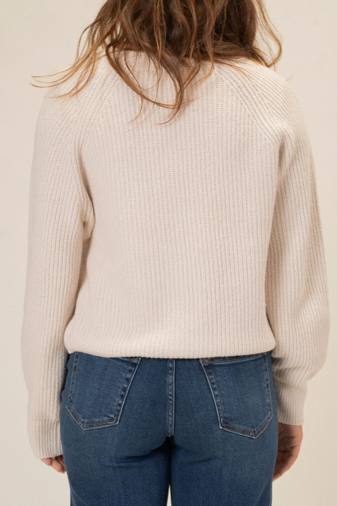 Ribbed beige knit cardigan with buttons, worn over light wash denim jeans.