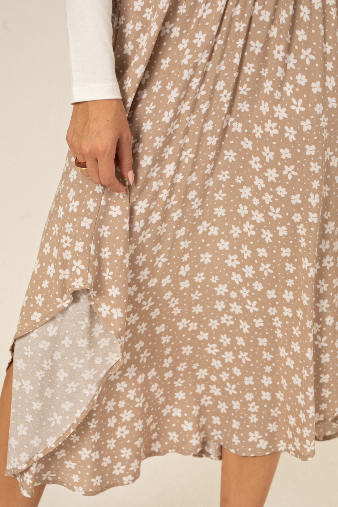 Tan floral-printed midi skirt with a round, asymmetric hemline and a fitted waist.