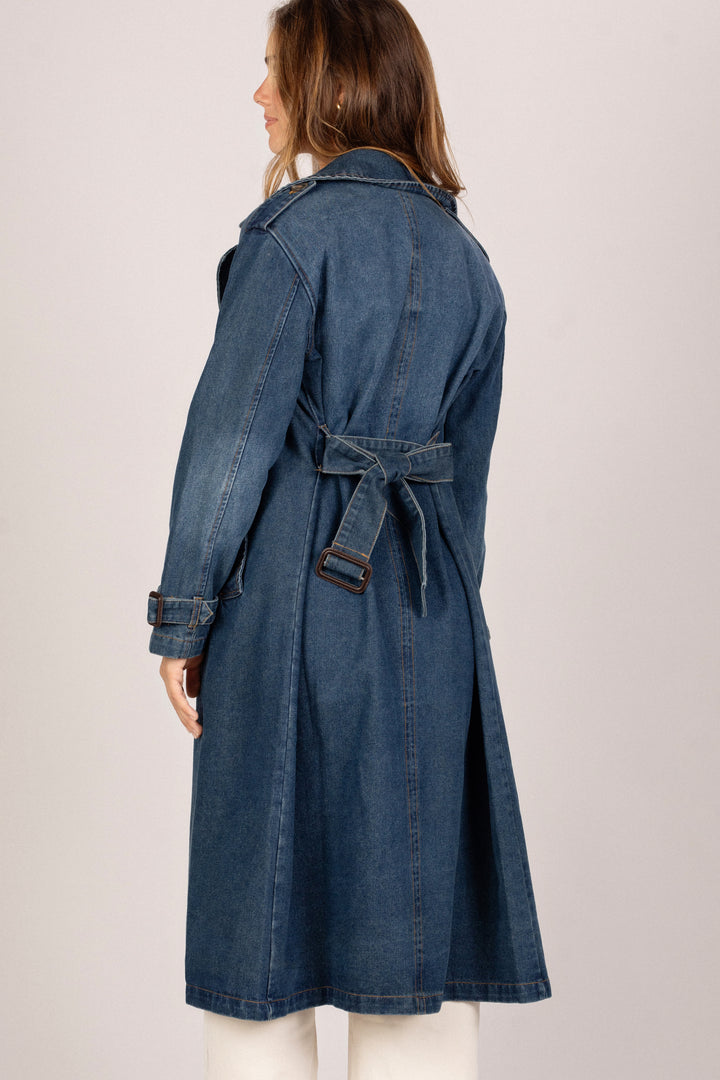 A long, denim trench coat with a belted waist and collared neckline, designed for a stylish, casual look.
