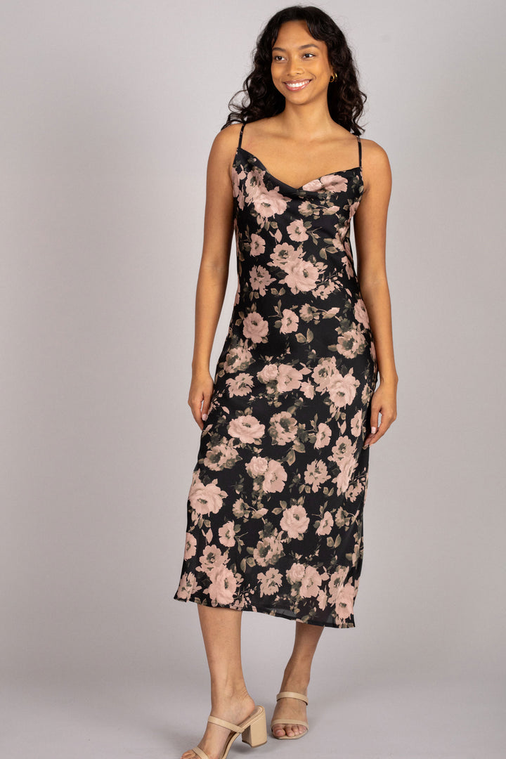 A floral slip dress in a black and pale pink floral pattern, with thin spaghetti straps and a midi-length silhouette.