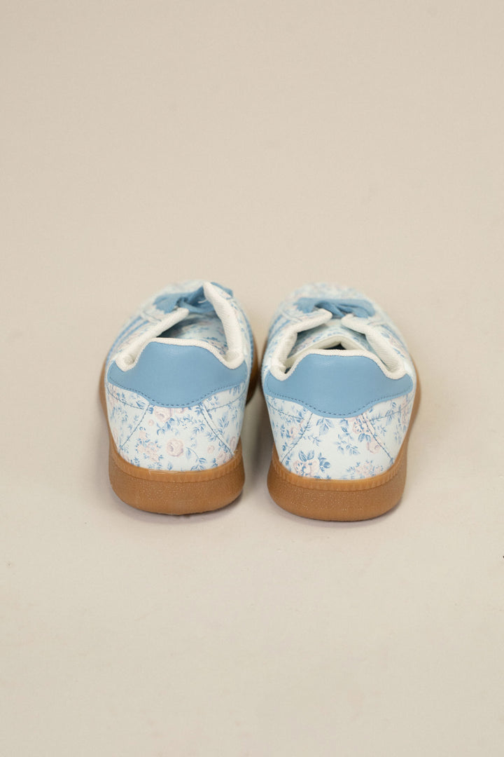 Pair of light blue floral print sneakers with lace-up closure and gum sole, showcasing a stylish and feminine design.