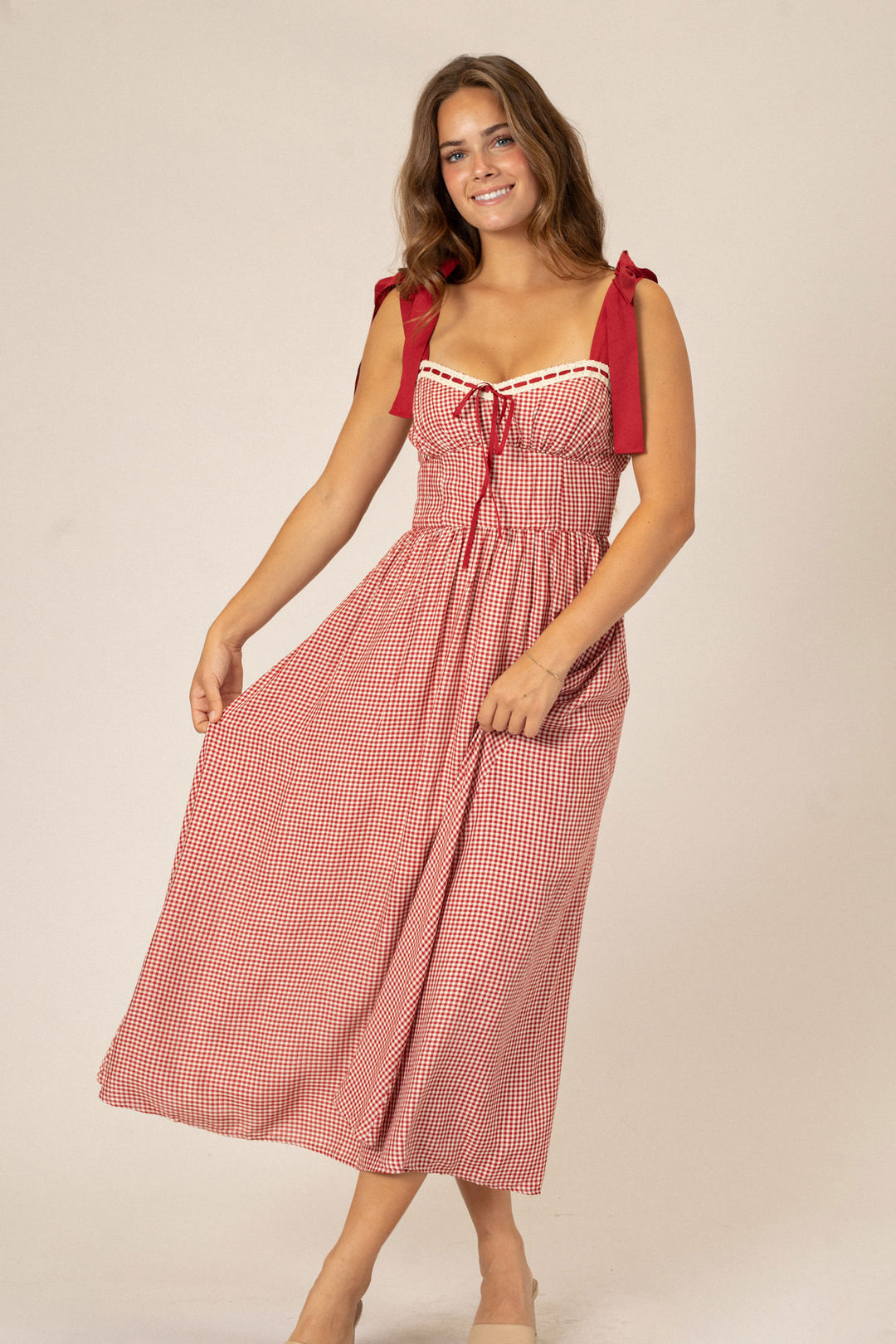 Vibrant red gingham dress with ruffle straps, tie waist, and sweetheart neckline, creating a charming and feminine look.