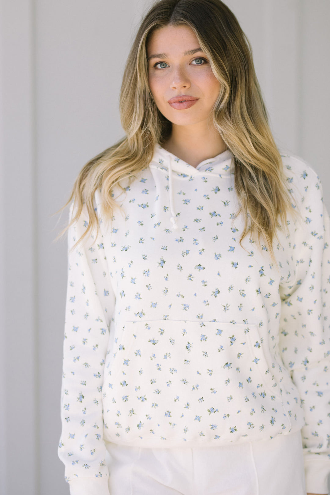A white floral hoodie sweatshirt with a feminine, soft floral print pattern and a cozy, comfortable design.