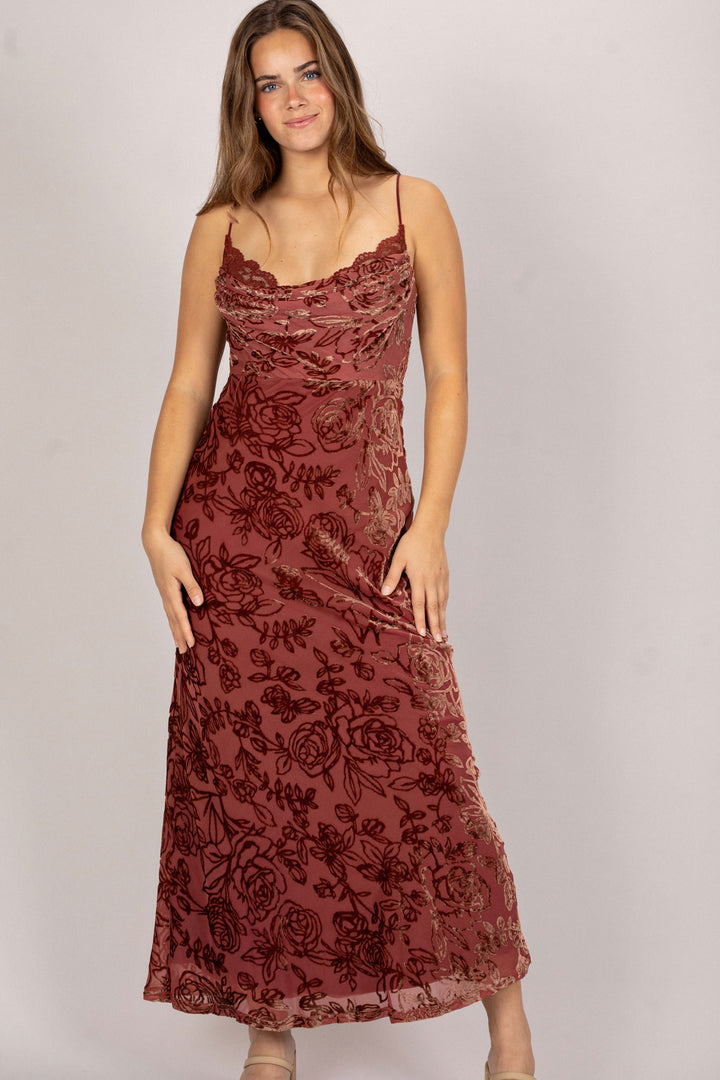 A long burgundy dress with intricate floral embroidery, featuring a cowl neckline and a flowing, ankle-length silhouette.