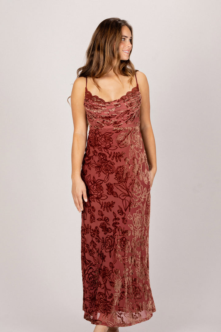 A sleeveless burgundy floral maxi dress with a cowl neckline and ruched detailing, creating a flattering silhouette.