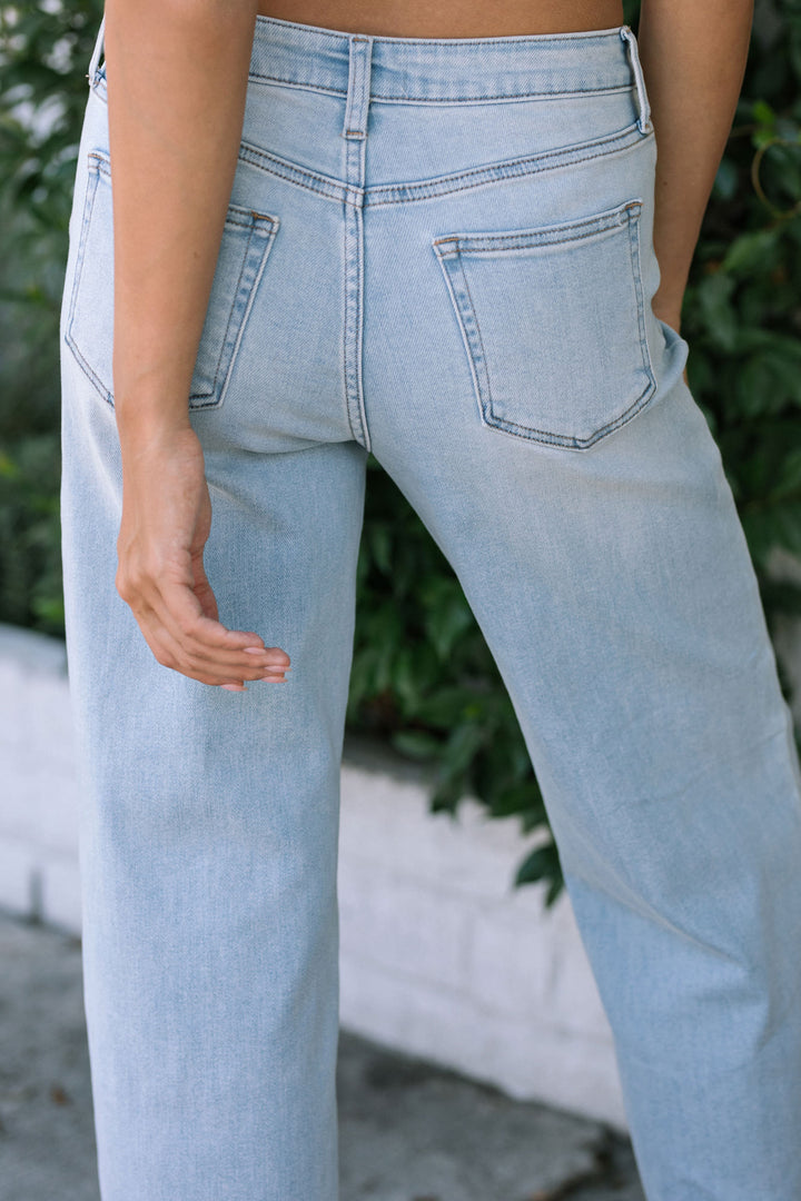 Close-up view of model's lower body wearing light blue wide leg jeans with pockets and a high waist.