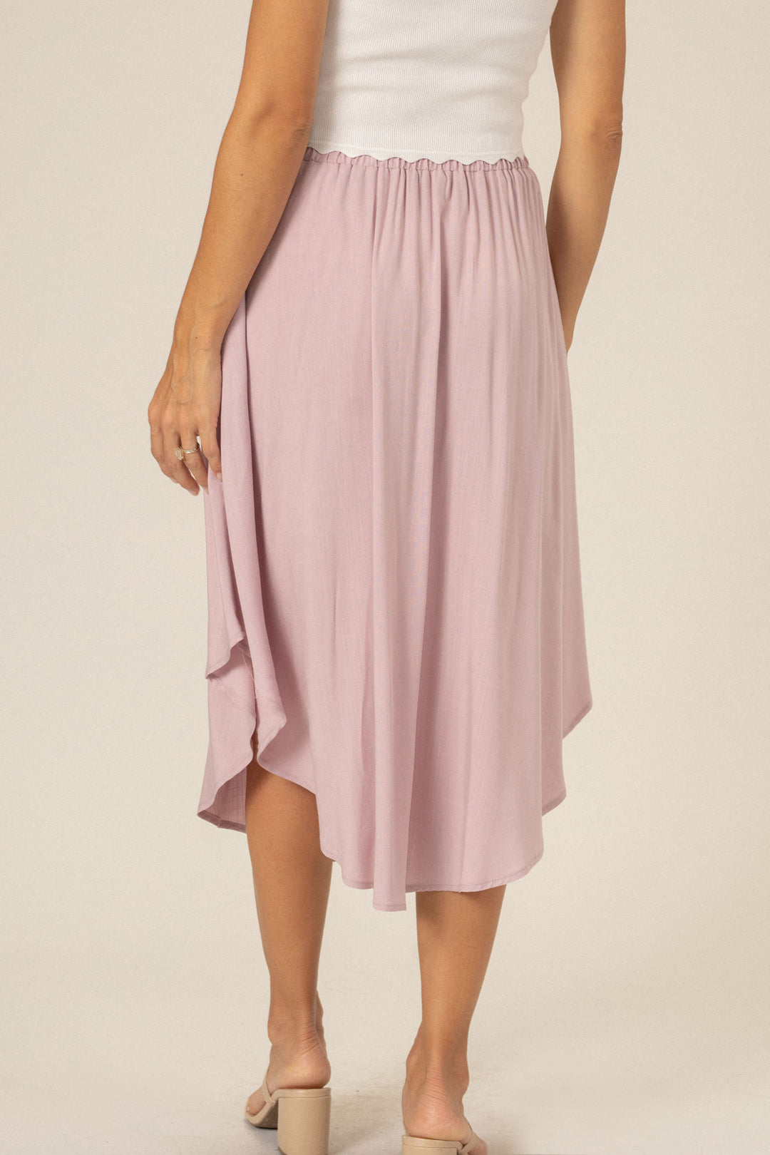 A pink, flowing midi skirt with a ruffled, rounded hemline.