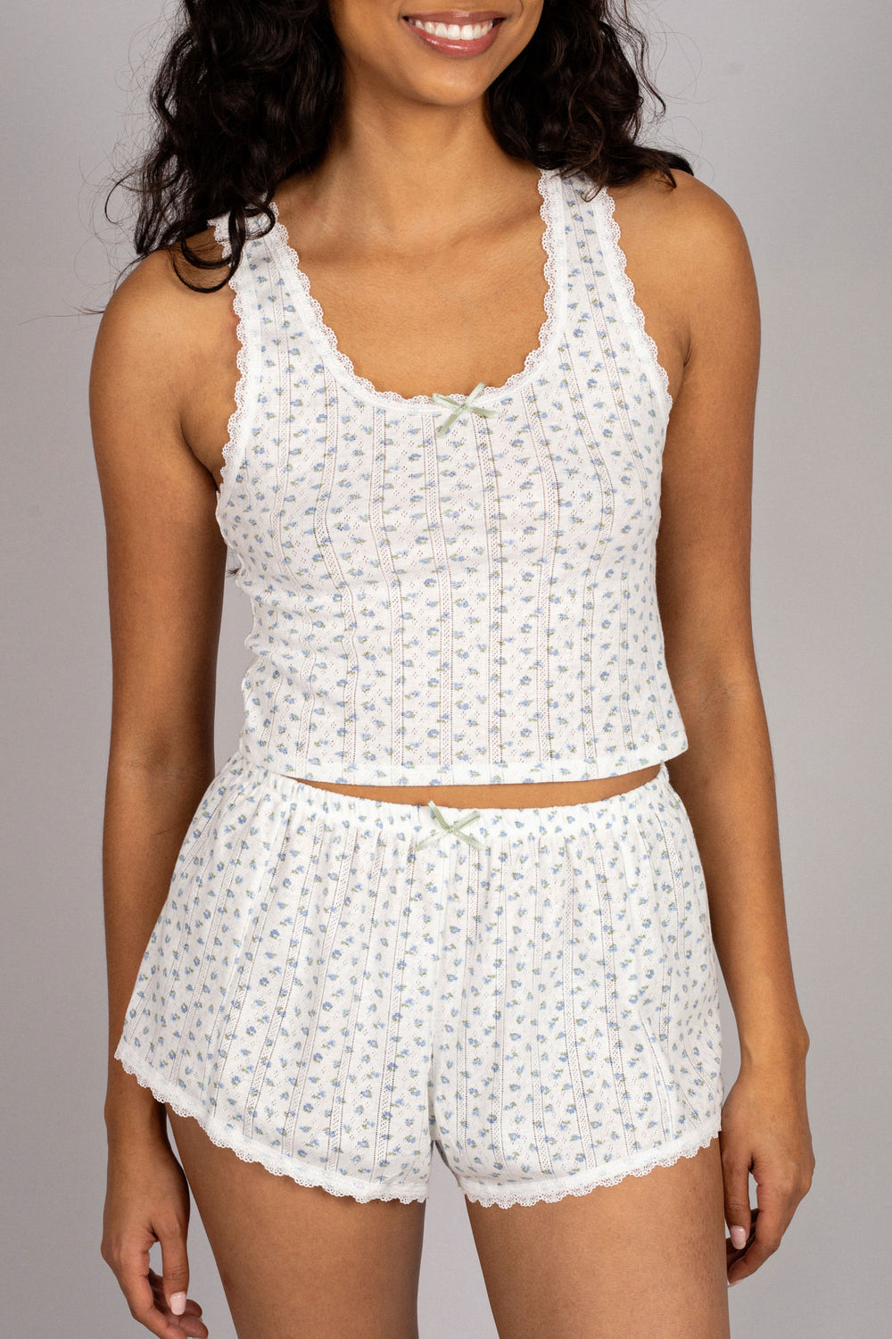 A white floral-printed, lace-trimmed sleeveless tank top and matching high-waisted shorts with an elastic drawstring waistband.