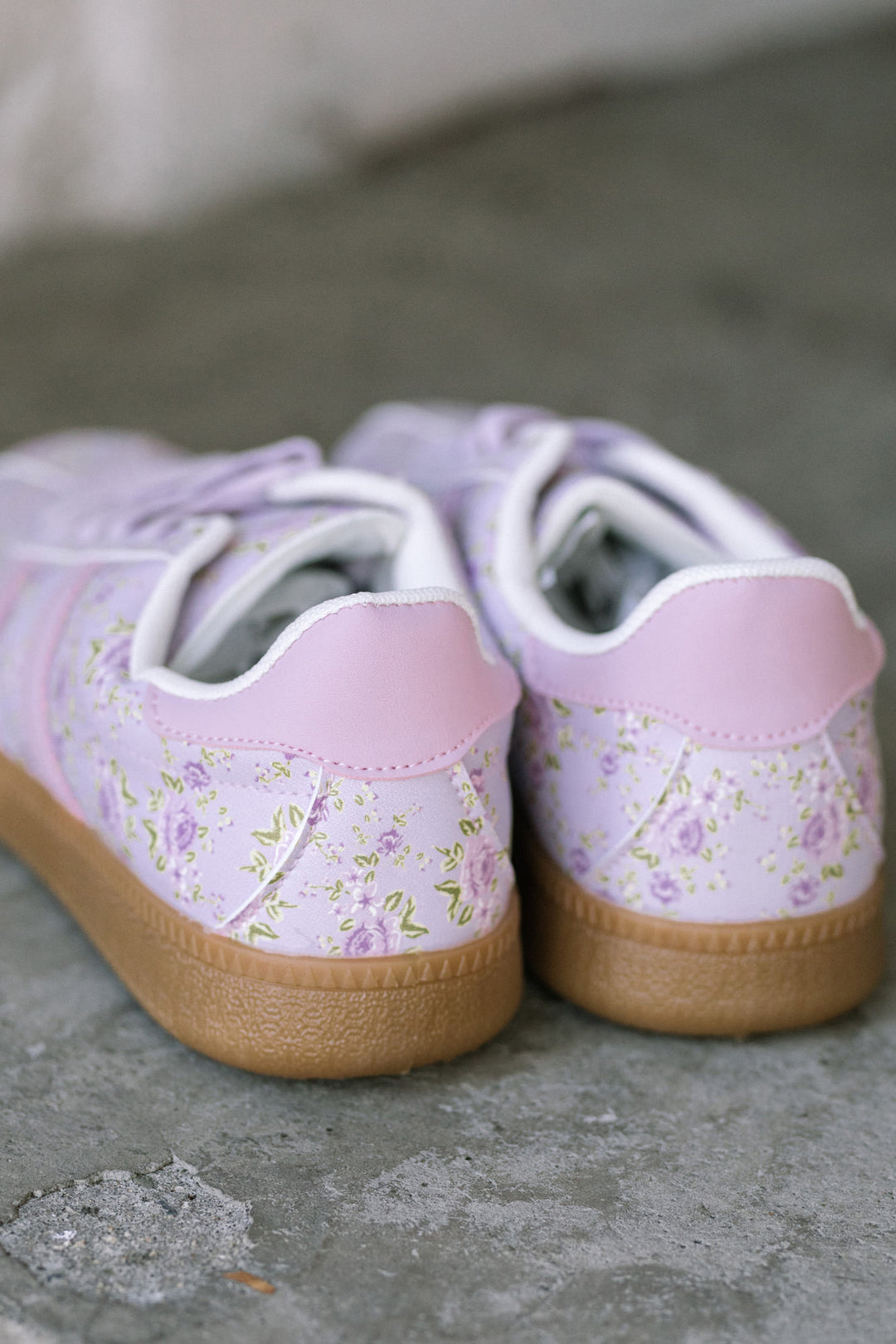 Lightweight floral-patterned sneakers in soft lilac and pink tones with lace-up closure and rubber sole.