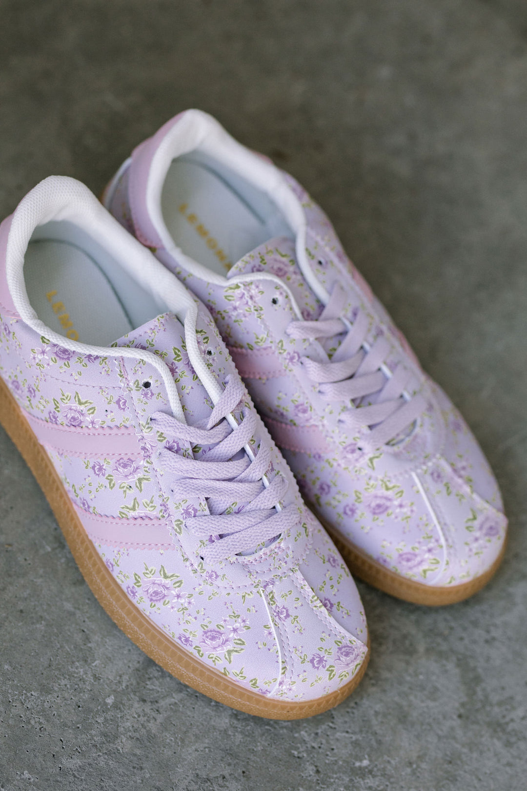 Lilac-colored sneakers with a delicate floral pattern, featuring a lace-up design and gum rubber soles.