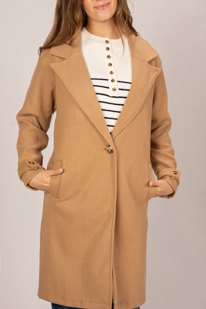 A camel-colored coat with a notched collar, featuring brass buttons and a relaxed, oversized fit.