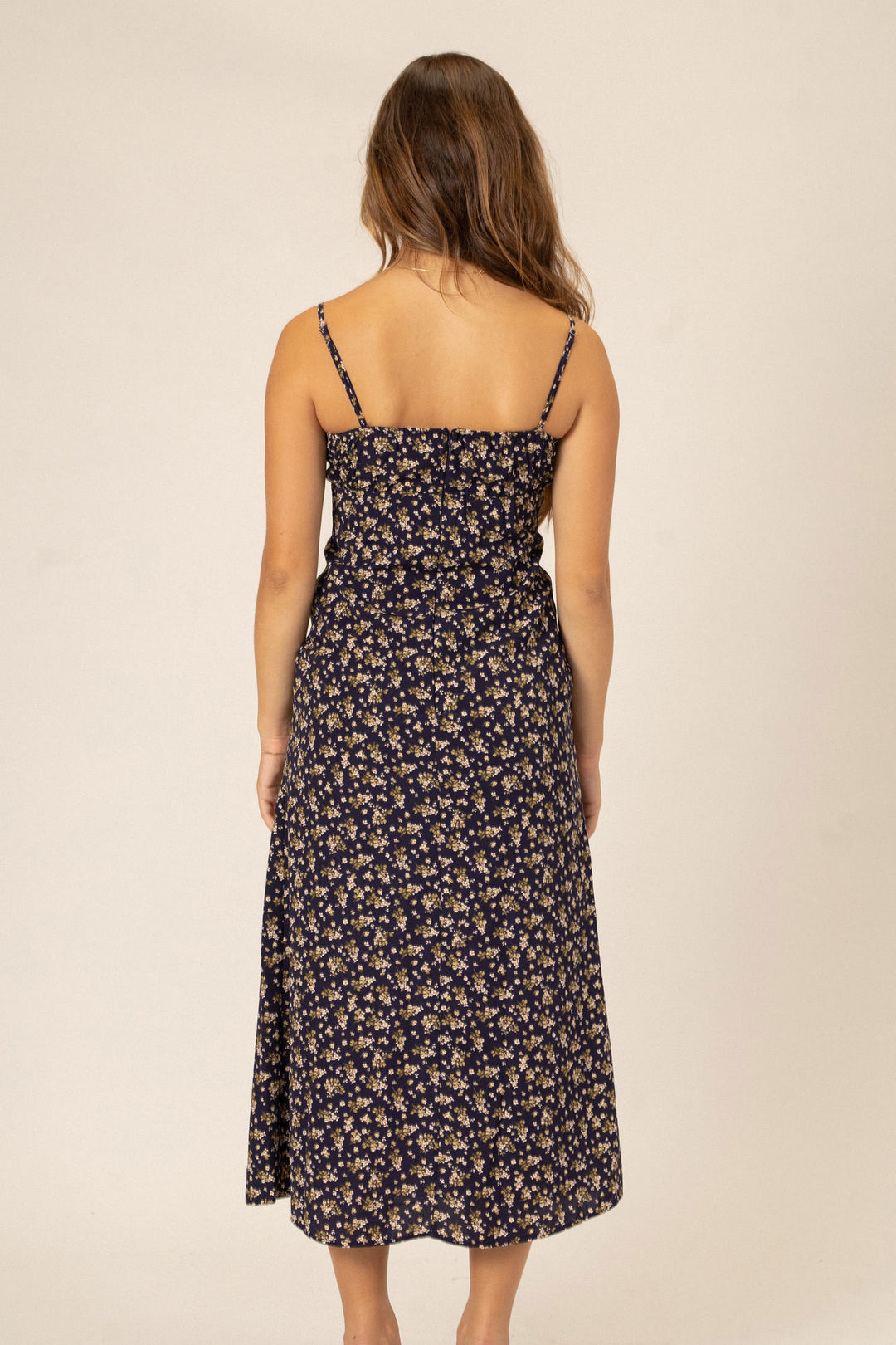 A navy blue midi dress with a floral print, thin spaghetti straps, and a fitted waist.