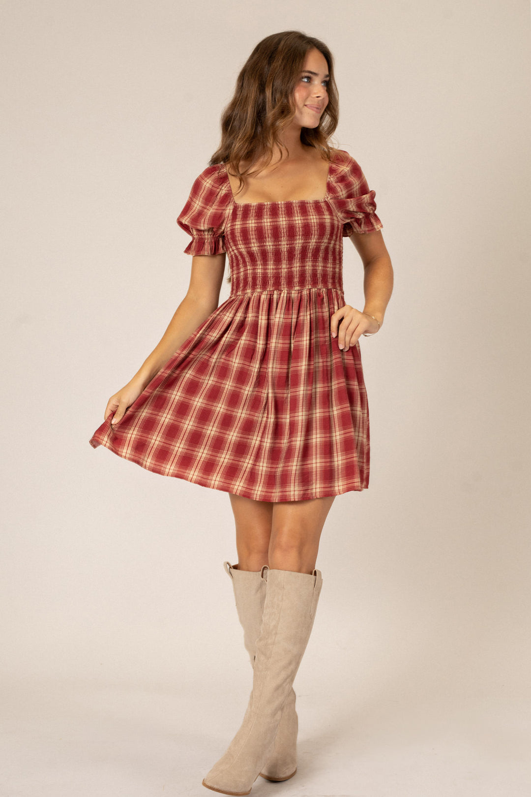 A red and white plaid mini dress with puff sleeves and a fitted bodice, paired with beige knee-high boots.