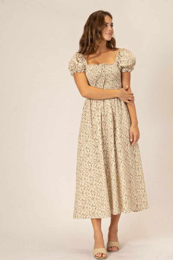 A white floral print dress with puff sleeves and a cinched waist, styled for a casual, feminine look.