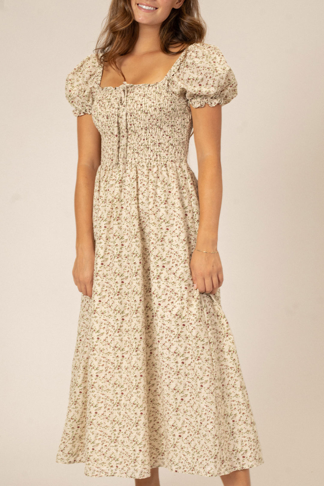 A floral-patterned midi dress with puffed sleeves, a smocked bodice, and a flowy, pleated skirt.
