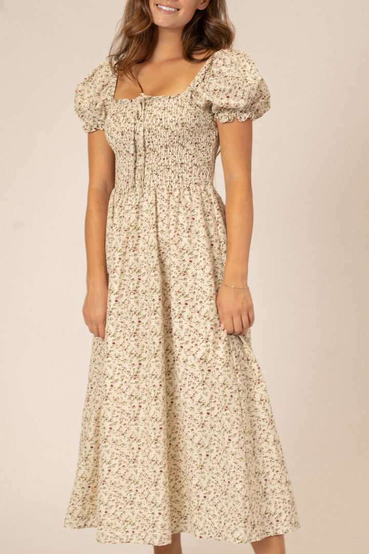 A floral-patterned midi dress with puffed sleeves, a smocked bodice, and a flowy, pleated skirt.