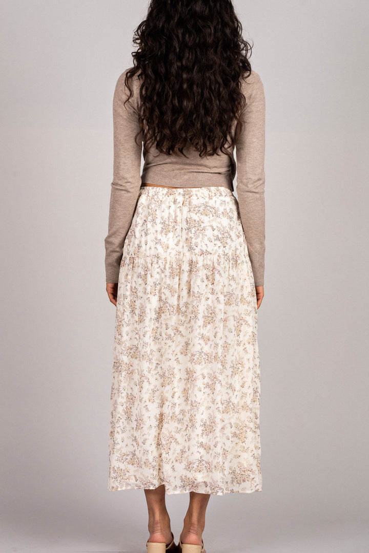 Flowing white floral midi skirt with taupe knit top, showcasing long dark curly hair.