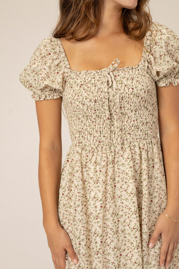 Floral puff-sleeved midi dress in neutral tones with a smocked bodice and ruffle detailing.