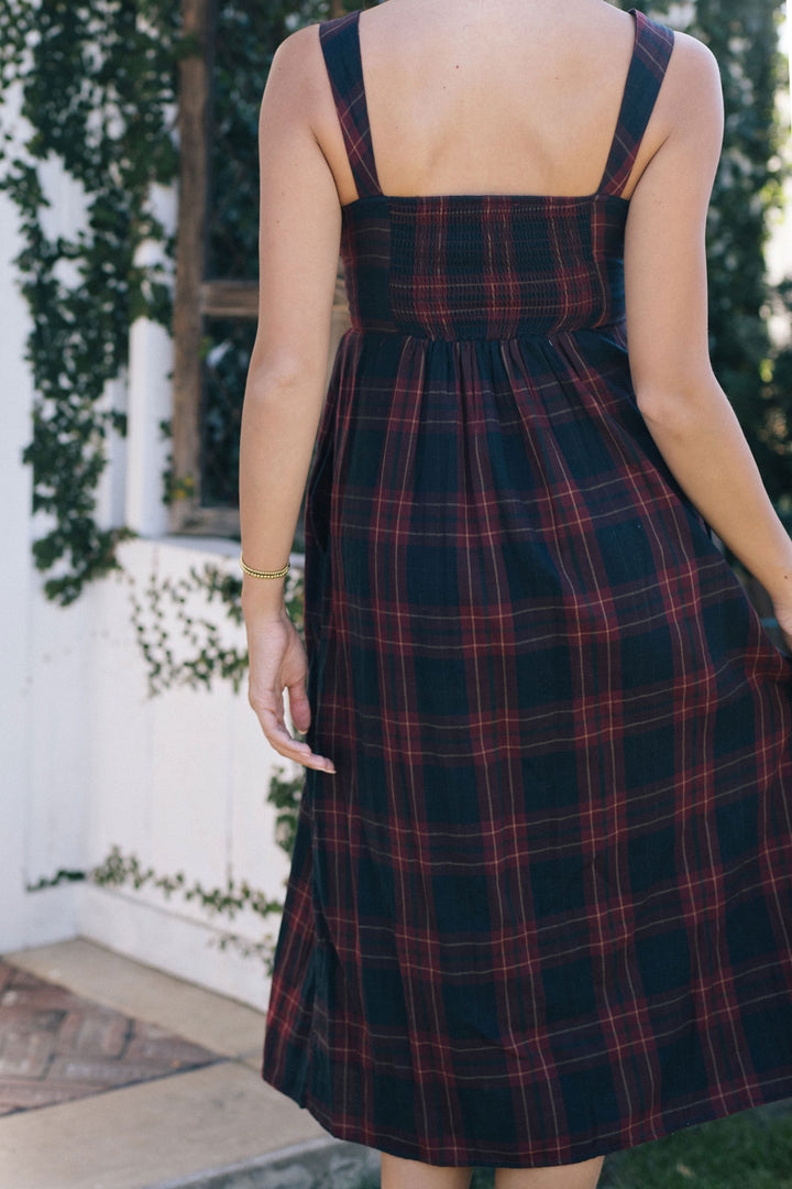 A navy and red plaid sleeveless midi dress with a shirred bodice and A-line silhouette.