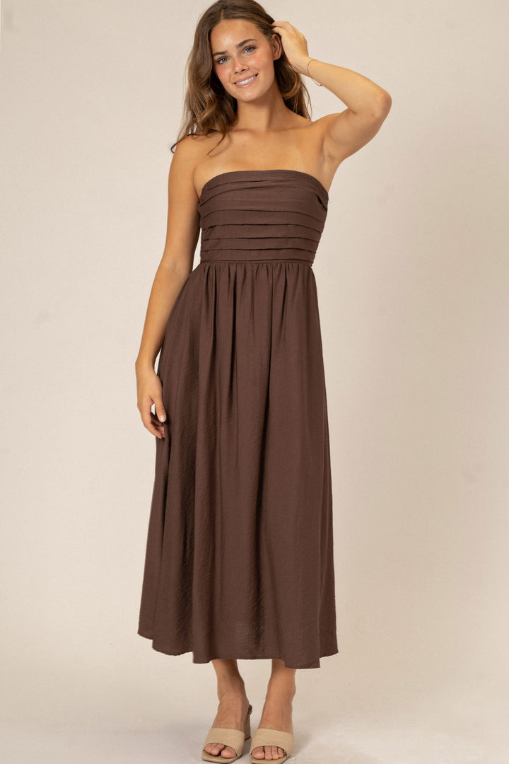 A strapless midi dress in a rich chocolate brown shade, featuring pleated detailing at the bodice and a flowing, A-line skirt.