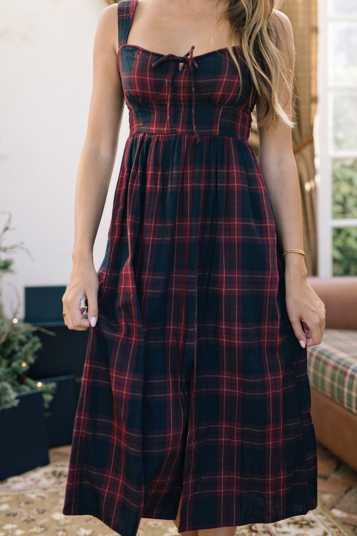 Woman wearing a red and black plaid dress indoors.