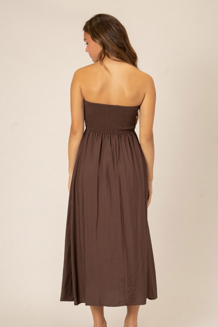 A brown midi dress with pleated bodice and flowing skirt, shown from the back view.