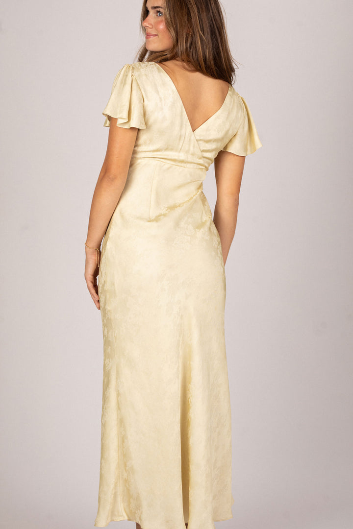 A yellow satin dress with flutter sleeves, a cinched waist, and a floor-length silhouette.