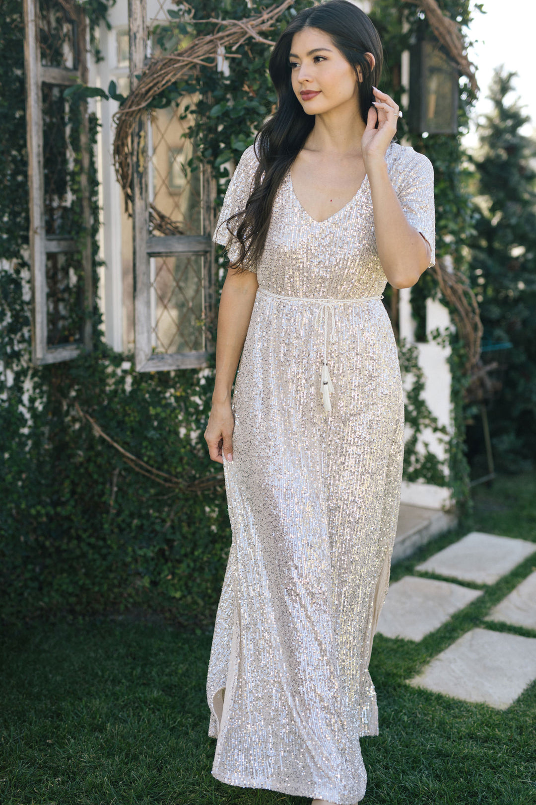 A long, shimmering silver sequin dress with a v-neck and short sleeves, perfect for formal events.