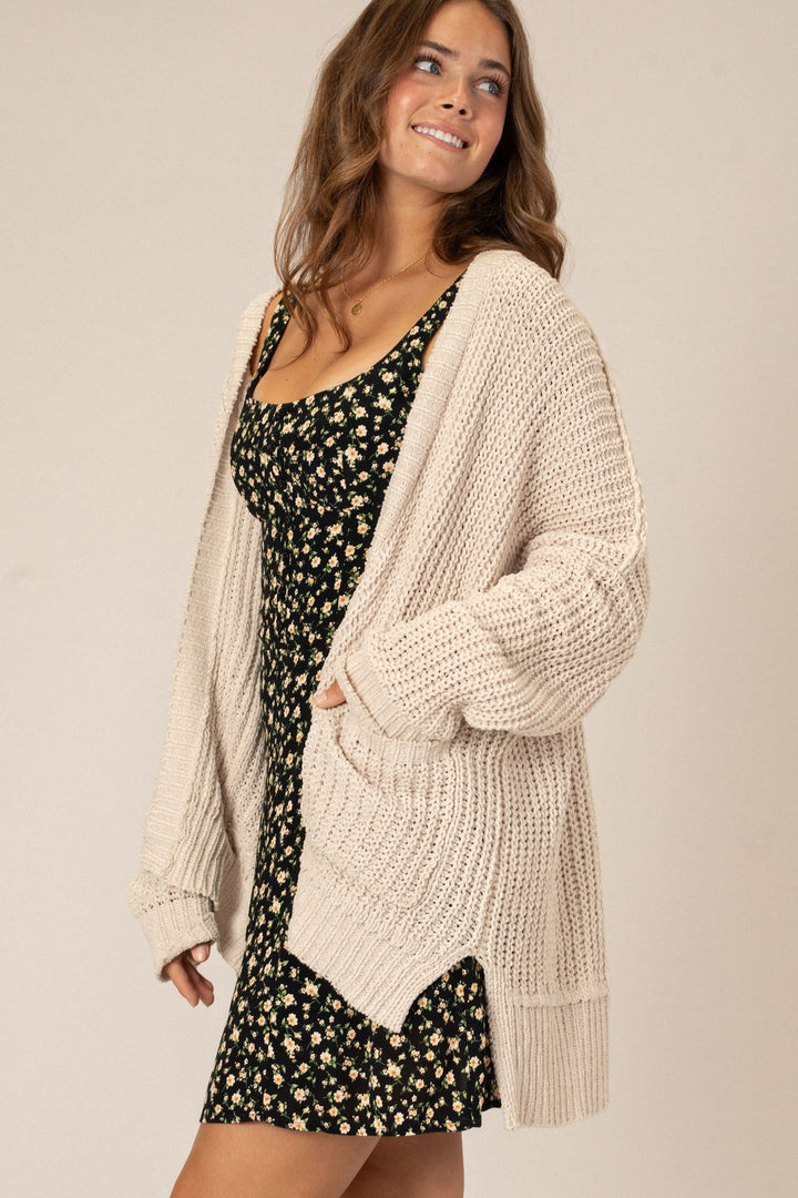 Cozy knit cardigan in a warm beige hue, featuring a relaxed, open-front design that drapes elegantly over the body.