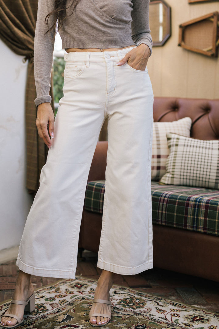 White cropped wide-leg jeans with high waist and pockets, worn with a gray long-sleeved top.