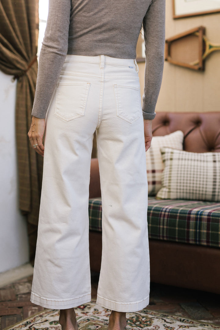 White wide-leg cropped jeans with pockets, paired with a grey knitted sweater.
