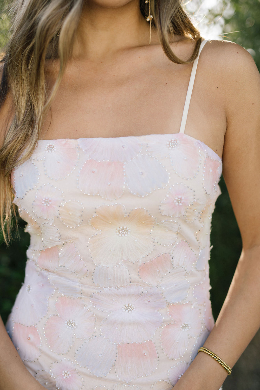 A white mini dress with intricate floral embroidery and shimmering sequin details, creating a romantic, feminine look.