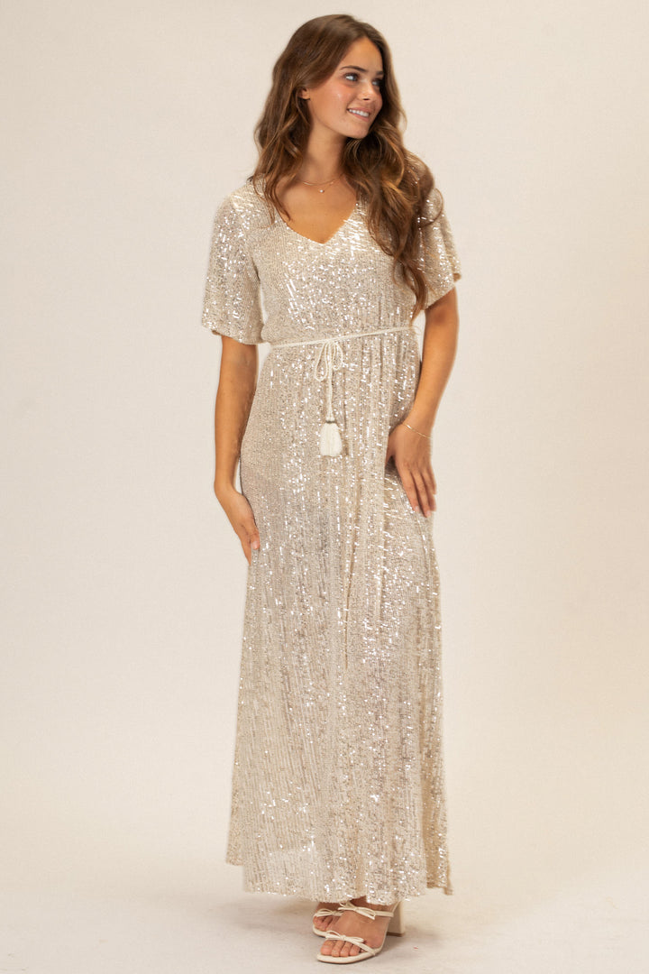 A silver sequin maxi dress with a v-neck and flared sleeves, creating a glamorous and sparkling evening look.