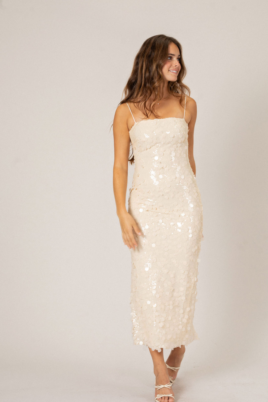 Elegant cream-colored sequin maxi dress with spaghetti straps, form-fitting silhouette, and ankle-length hem.