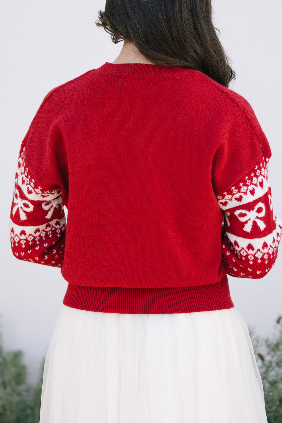 A bright red knit sweater with a festive white snowflake pattern on the sleeves, creating a cozy and stylish winter look.