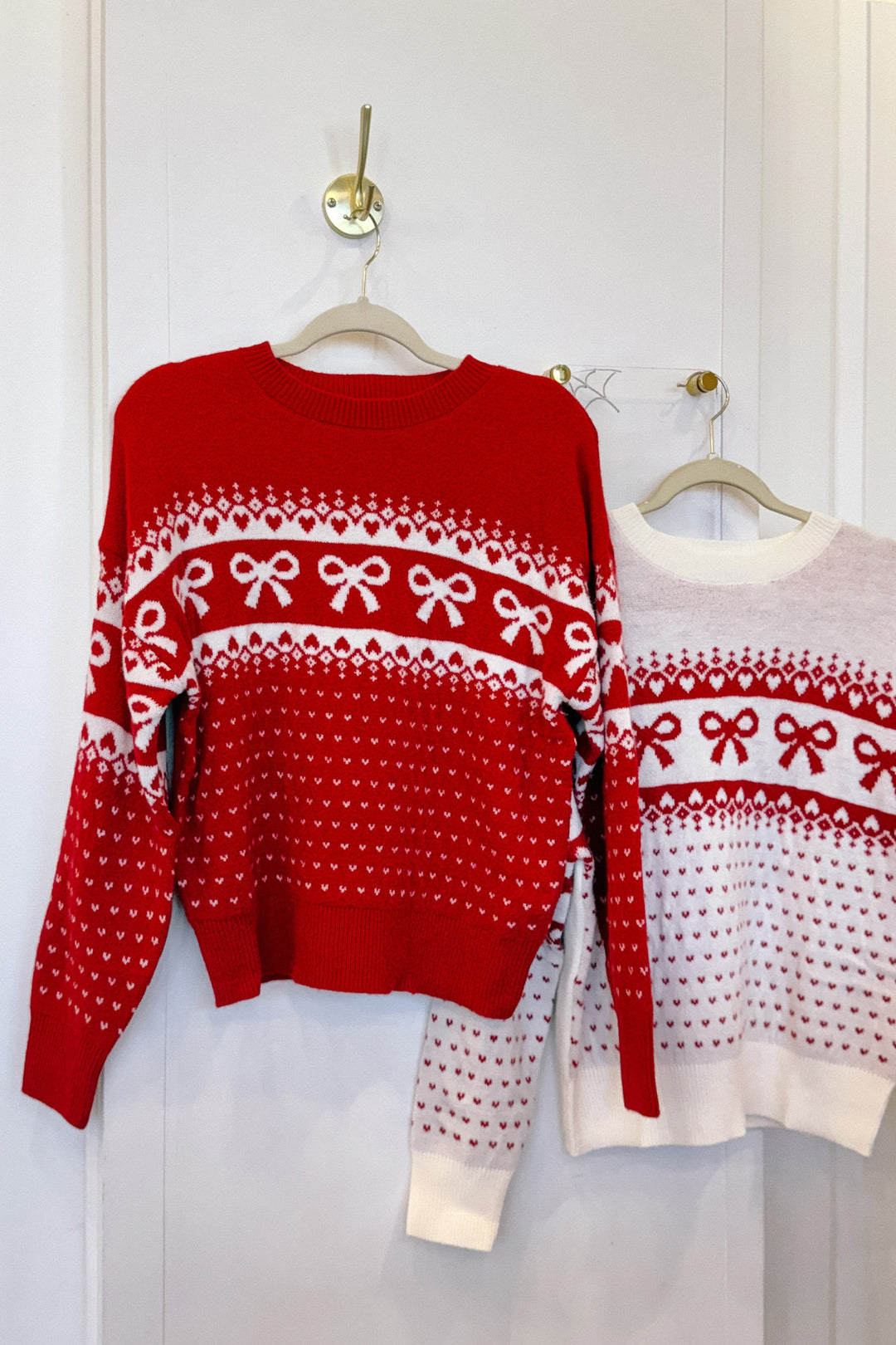 Red and white knit sweater with repeating bow pattern, available in small to large sizes.