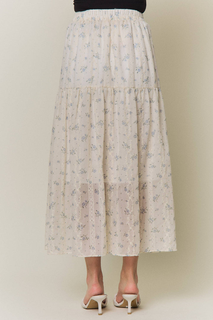 Cream floral tiered maxi skirt, back view, with black crop top and cream heels.