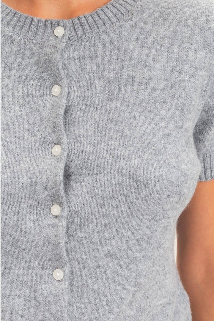 A close-up of a person wearing a light gray short-sleeve knit cardigan with a button-front closure and ribbed crew neckline.