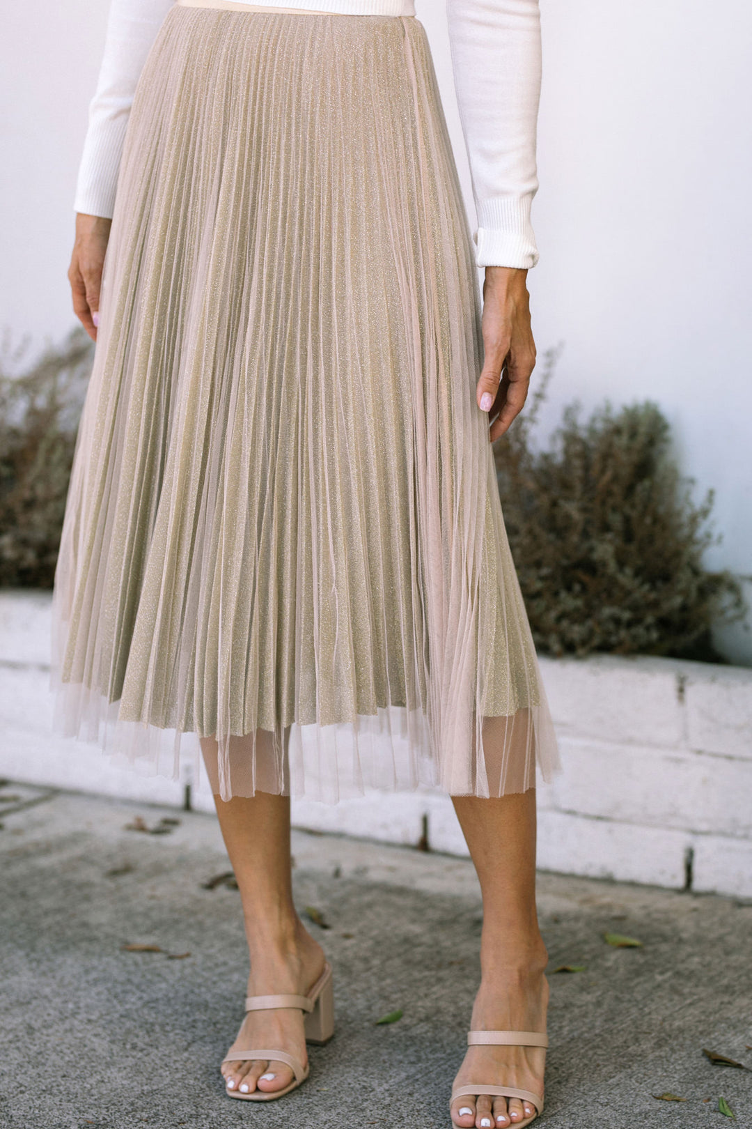 Gold pleated midi skirt with sheer overlay and ankle strap sandals.