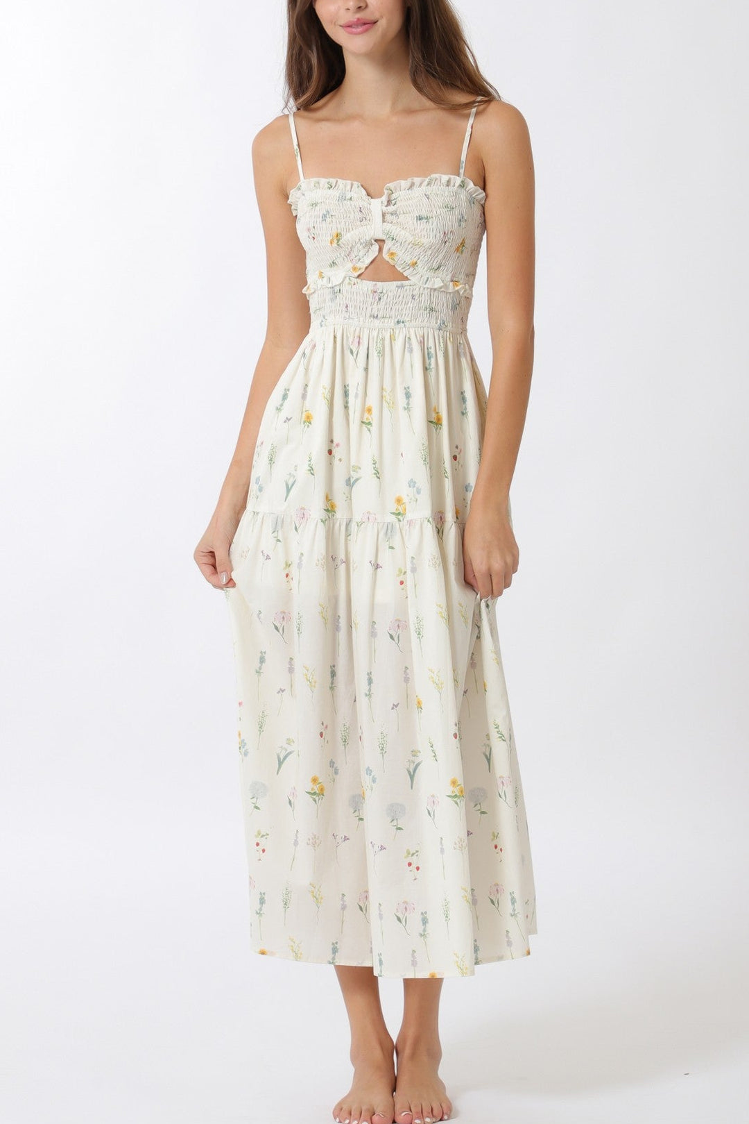 A white maxi dress with a floral print, smocked bodice, and thin shoulder straps, creating a whimsical and feminine look.