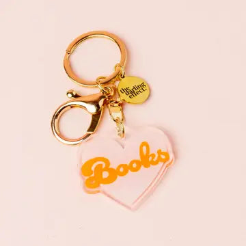 A heart-shaped acrylic keychain with "Books" written in yellow text, adorned with a gold-tone metal ring.
