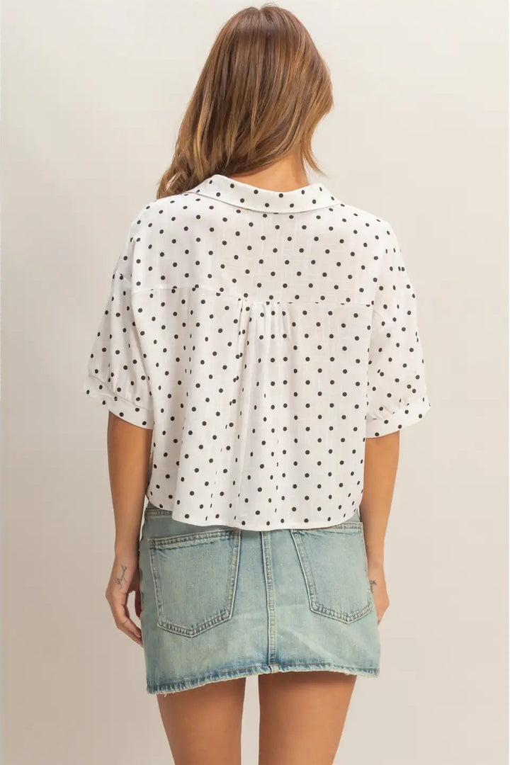 A relaxed-fit, white button-up shirt with black polka dots, short sleeves, and a loose, breezy silhouette.