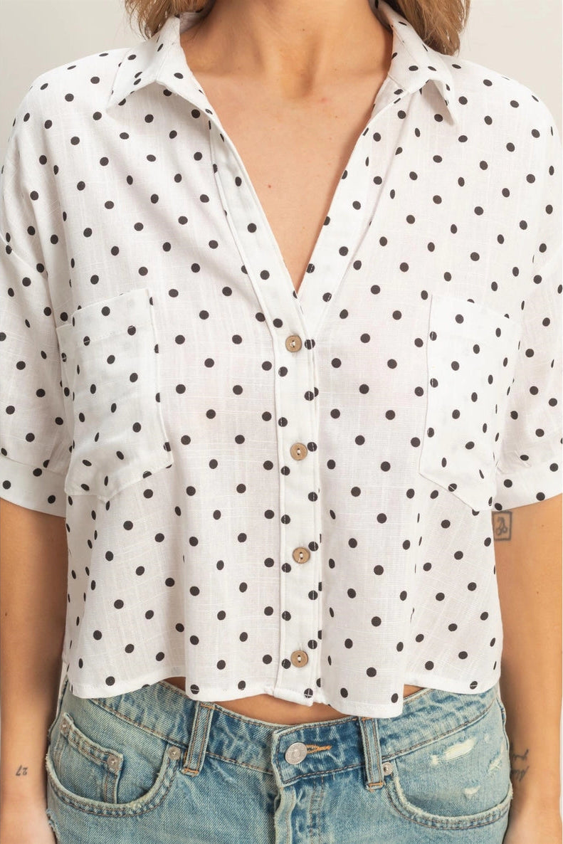 A relaxed-fit, white button-up shirt with a black polka dot pattern and short sleeves.
