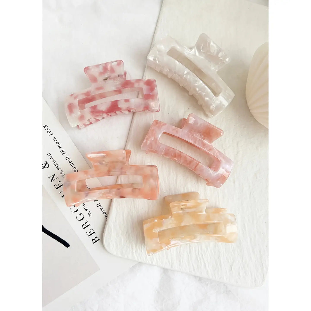 Assorted pink and beige rectangular hair clips with a tortoiseshell-like pattern, showcased against a white background.