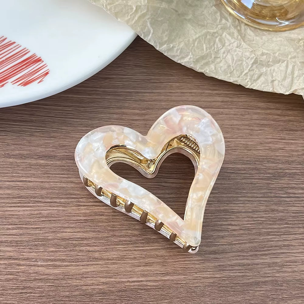Amber-colored heart-shaped hair claw clip with metal teeth and gold-tone accents.